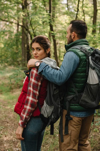 Hombre abrazando mujer mientras senderismo en el bosque juntos - foto de stock
