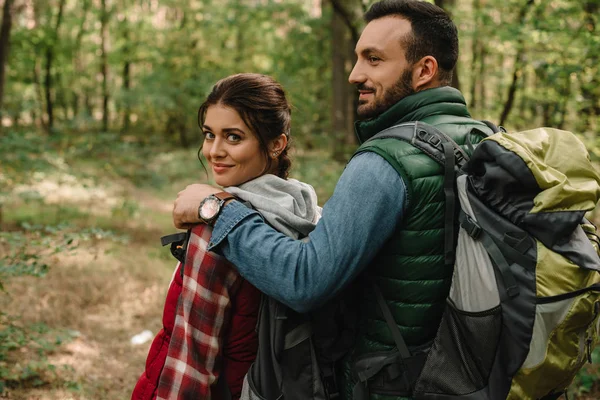 Smiling man hugging woman while hiking in forest together — Stock Photo