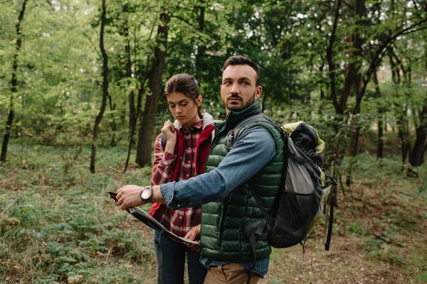 Couple of travelers with map got lost in woods — Stock Photo