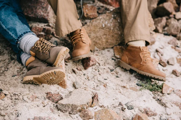 Cropped shot of couple of travelers resting on rocks on sandy beach — Stock Photo