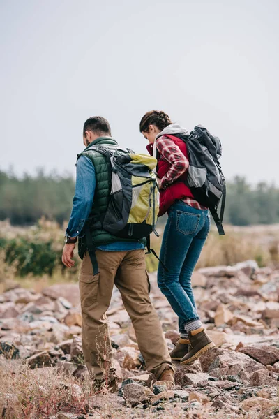 Excursionistas con mochilas caminando sobre piedras - foto de stock