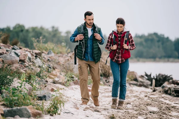 Wanderer mit Rucksäcken spazieren gemeinsam am Sandstrand — Stockfoto