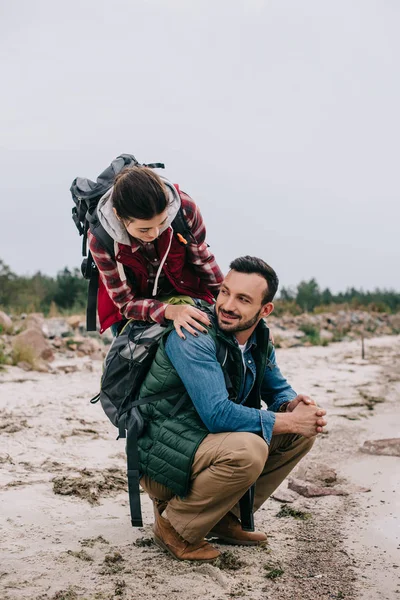 Couple of hikers with backpacks on sandy beach — Stock Photo