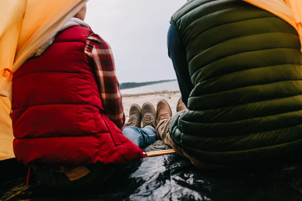 Vue arrière du couple assis dans une tente de camping sur une plage de sable — Photo de stock