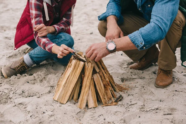 Couple making campfire on sandy beach — Stock Photo