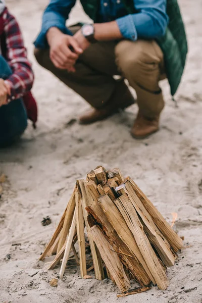 Пара разводит костер на песчаном пляже — стоковое фото
