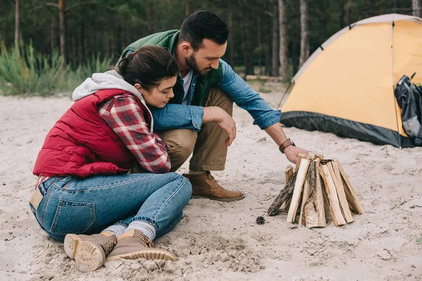 Couple making campfire on sandy beach — Stock Photo