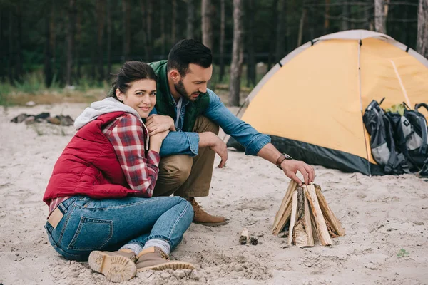 Casal fazendo fogueira na praia de areia — Fotografia de Stock