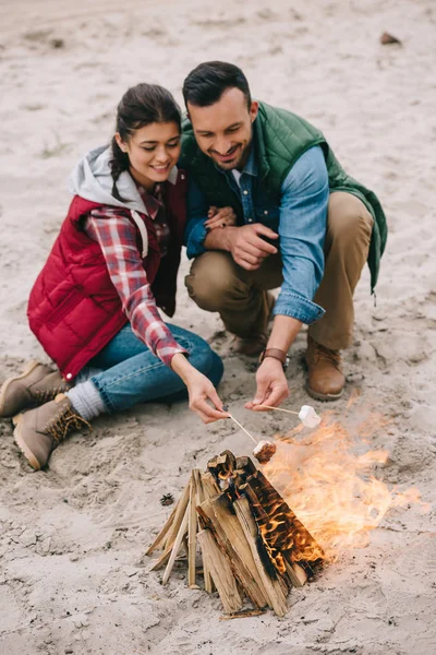 Couple torréfaction guimauve sur feu de camp sur la plage de sable fin — Photo de stock