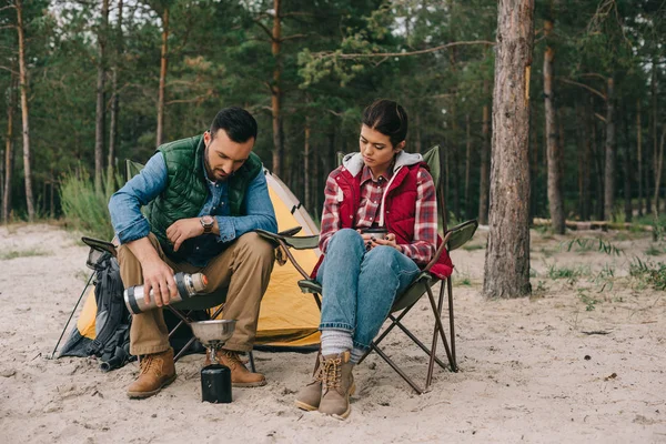 Pareja teniendo camping en playa de arena con bosque de pinos detrás - foto de stock