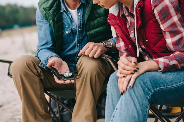 Cropped shot of couple with compass sitting on chairs on camping — Stock Photo