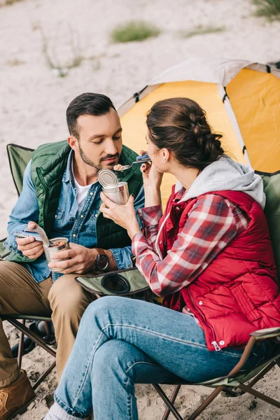 Woman feeding husband while having camping together — Stock Photo