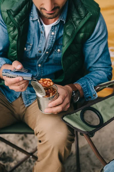 Cropped shot of traveler eating food from can during hiking — Stock Photo