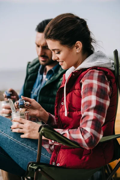 Couple eating food from cans while having camping — Stock Photo