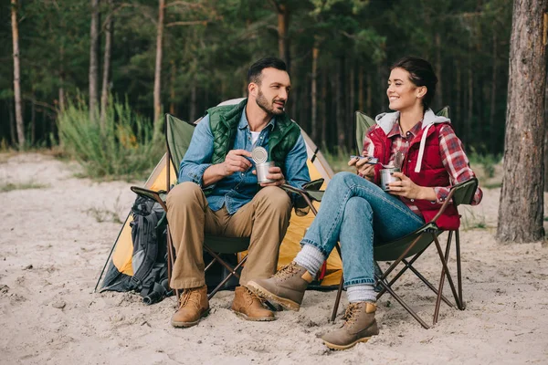 Pareja comiendo comida de latas mientras acampan - foto de stock