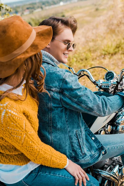 Happy couple sitting on vintage motorbike on rural meadow — Stock Photo