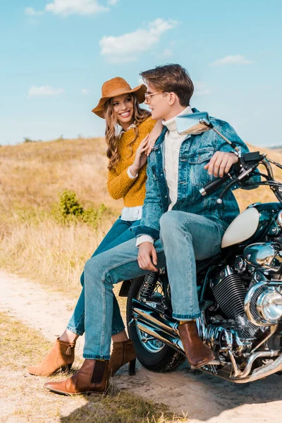 Молода пара, дивлячись один на одного і, сидячи на ретро мотоцикл — стокове фото