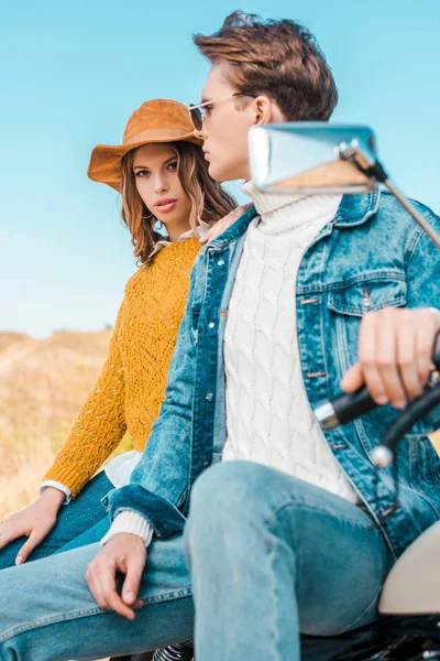 Attractive couple sitting on retro motorbike on rural meadow — Stock Photo