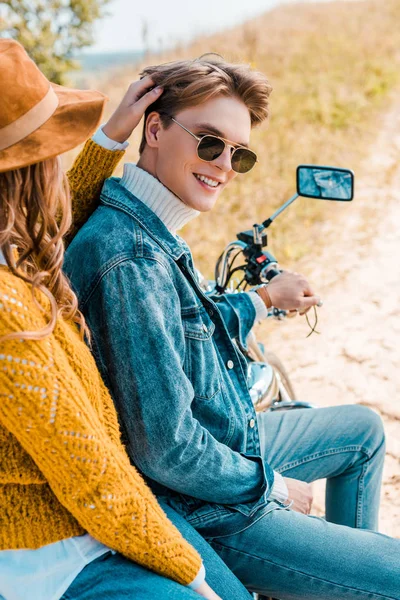 Pareja elegante sentado en moto vintage mientras que la novia tocando el pelo del novio - foto de stock