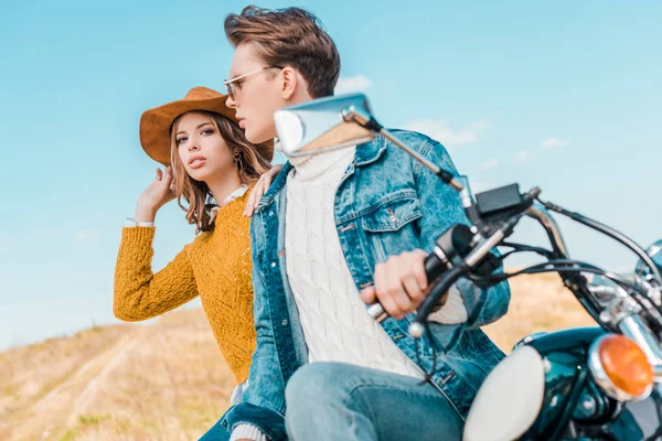 Stylish couple sitting on vintage motorbike against blue sky — Stock Photo