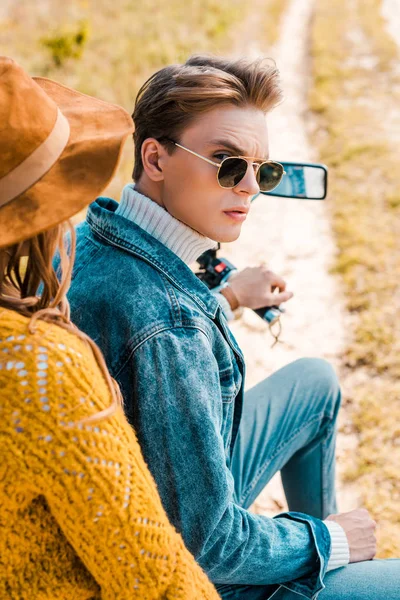 Jovem casal elegante sentado em moto no prado rural — Fotografia de Stock