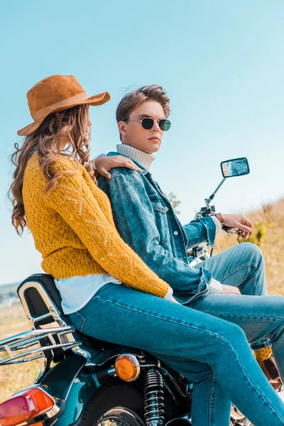 Joven pareja sentado en moto y relajarse en el prado rural - foto de stock