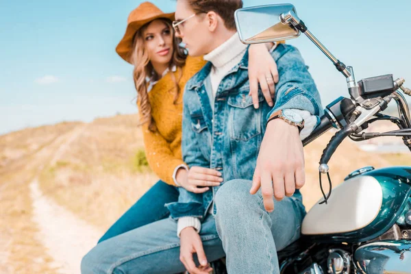Jeune couple assis sur moto vintage sur prairie rurale — Photo de stock
