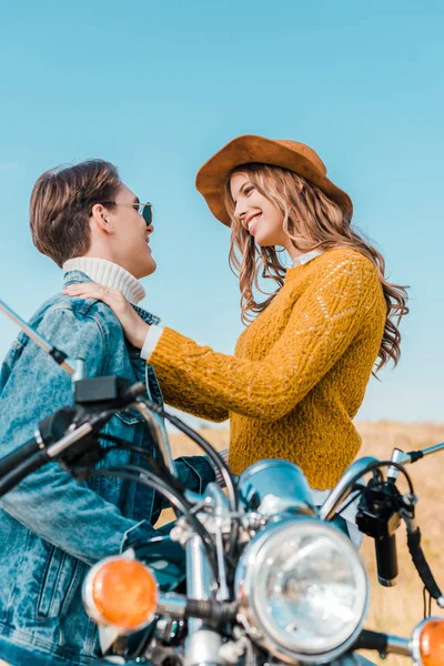 Улыбающаяся пара, глядя друг на друга и сидя на мотоцикле — стоковое фото