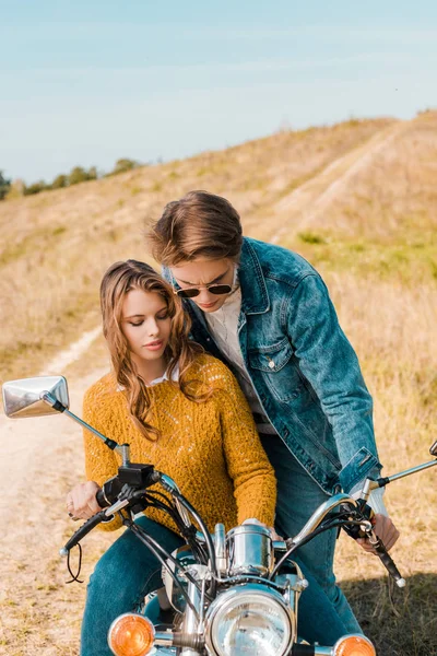Молода пара дивиться на ретро мотоцикл на лузі — стокове фото