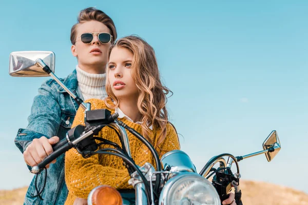 Happy couple sitting on motorbike against blue sky — Stock Photo