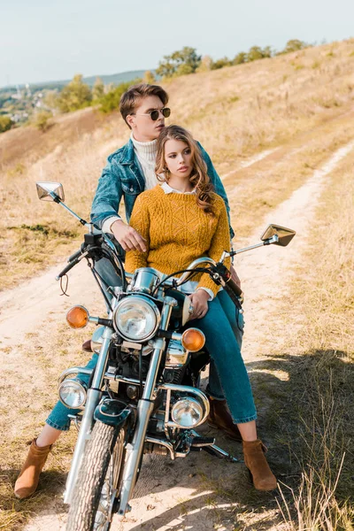 Beautiful couple of travelers hugging and sitting on retro motorbike — Stock Photo