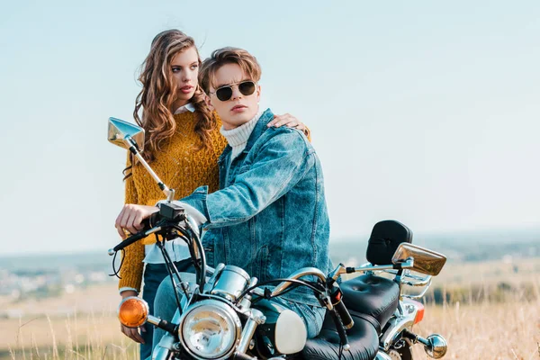 Jovem namorada abraçando namorado enquanto sentado na motocicleta vintage — Fotografia de Stock