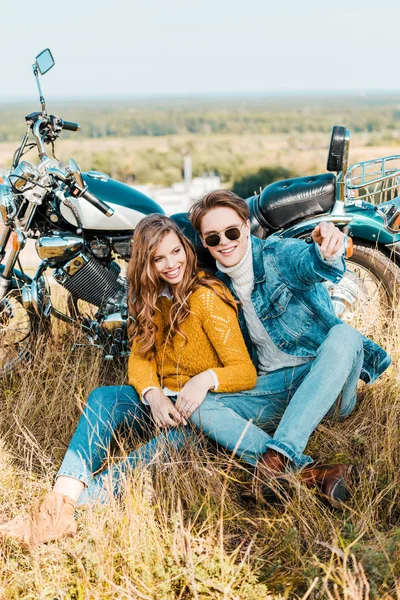 Sorrindo casal sentado perto de moto retro — Fotografia de Stock