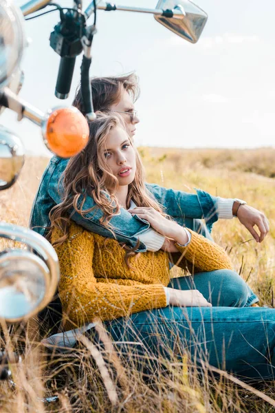 Novio abrazando novia y sentado cerca de retro moto - foto de stock