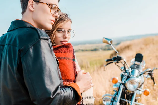 Молода пара в окулярах стоїть біля старовинного мотоцикла — стокове фото