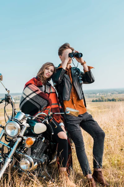 Jovem namorado olhando através binóculos perto namorada sentado em moto — Fotografia de Stock