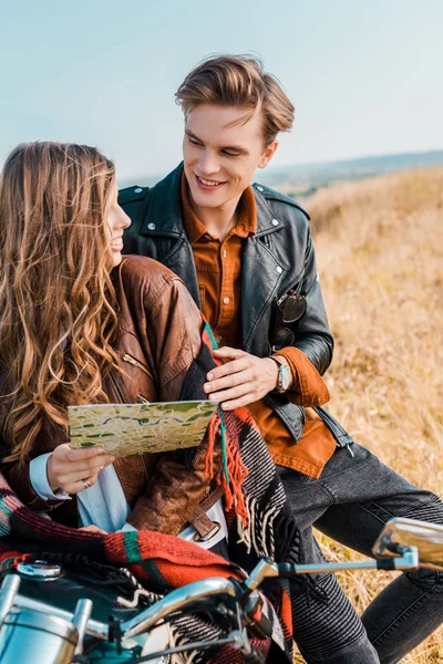 Giovane fidanzata in possesso di mappa vicino bello fidanzato seduto su moto — Foto stock