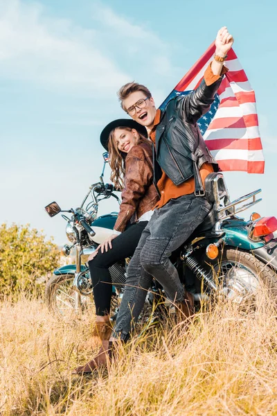 Coppia felice con bandiera americana seduta sul prato, concetto di indipendenza — Foto stock