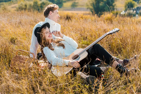 Feliz jovem casal com guitarra relaxante no prado — Fotografia de Stock