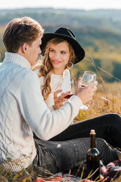 Молодая пара звонкая с бокалами красного вина и расслабляющая на лугу — стоковое фото