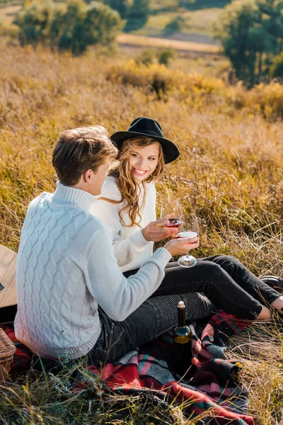 Casal sorrindo clinking com copos de vinho tinto durante piquenique no prado rural — Fotografia de Stock