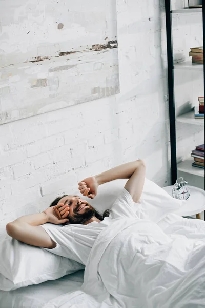 Visão de alto ângulo do homem barbudo acordando na cama durante o horário da manhã em casa — Fotografia de Stock