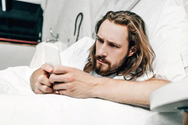 Selective focus of focused Jesus using smartphone in bedroom at home — Stock Photo