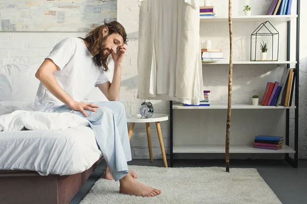 Upset Jesus sitting on bed during morning time in bedroom at home — Stock Photo