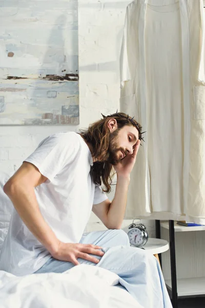 Selective focus of upset Jesus sitting on bed during morning time in bedroom at home — Stock Photo