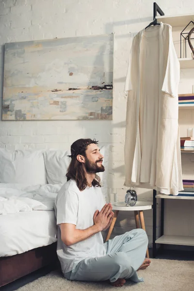 Happy Jesus in crown of thorns sitting on floor in lotus position during morning time at home — Stock Photo