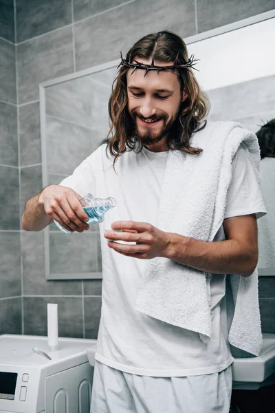 Smiling Jesus in crown of thorns pouring moutwash liquid in bathroom — Stock Photo