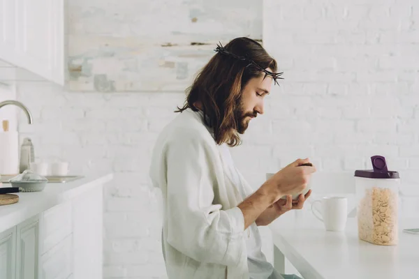 Seitenansicht des Jesus essen Cornflakes auf Frühstück in der Küche zu Hause — Stockfoto