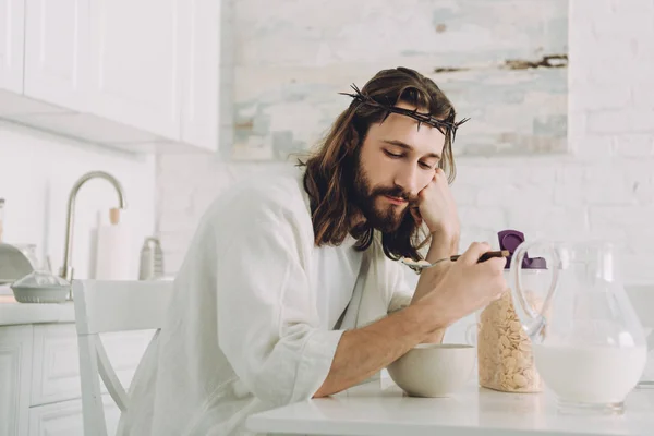 Tired Jesus eating corn flakes on breakfast in kitchen at home — Stock Photo