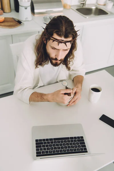 High angle view of Jesus eating corn flakes on breakfast at table with laptop in kitchen at home — Stock Photo